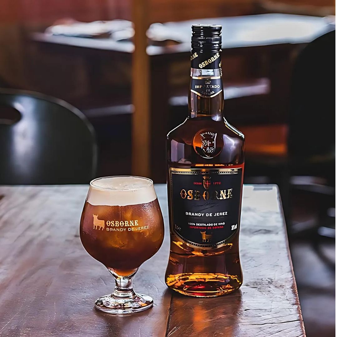 Garrafa de Brandy Osborne ao lado de uma taça com a bebida servida.