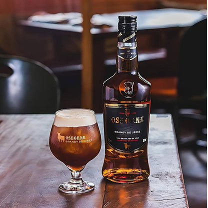 Garrafa de Brandy Osborne ao lado de uma taça com a bebida servida.