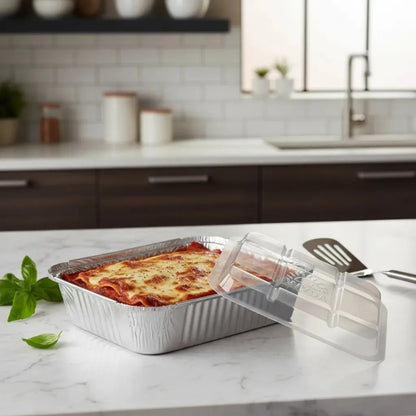 Marmitex de aluminio com lasanha e tampa transparente apoiada ao lado.