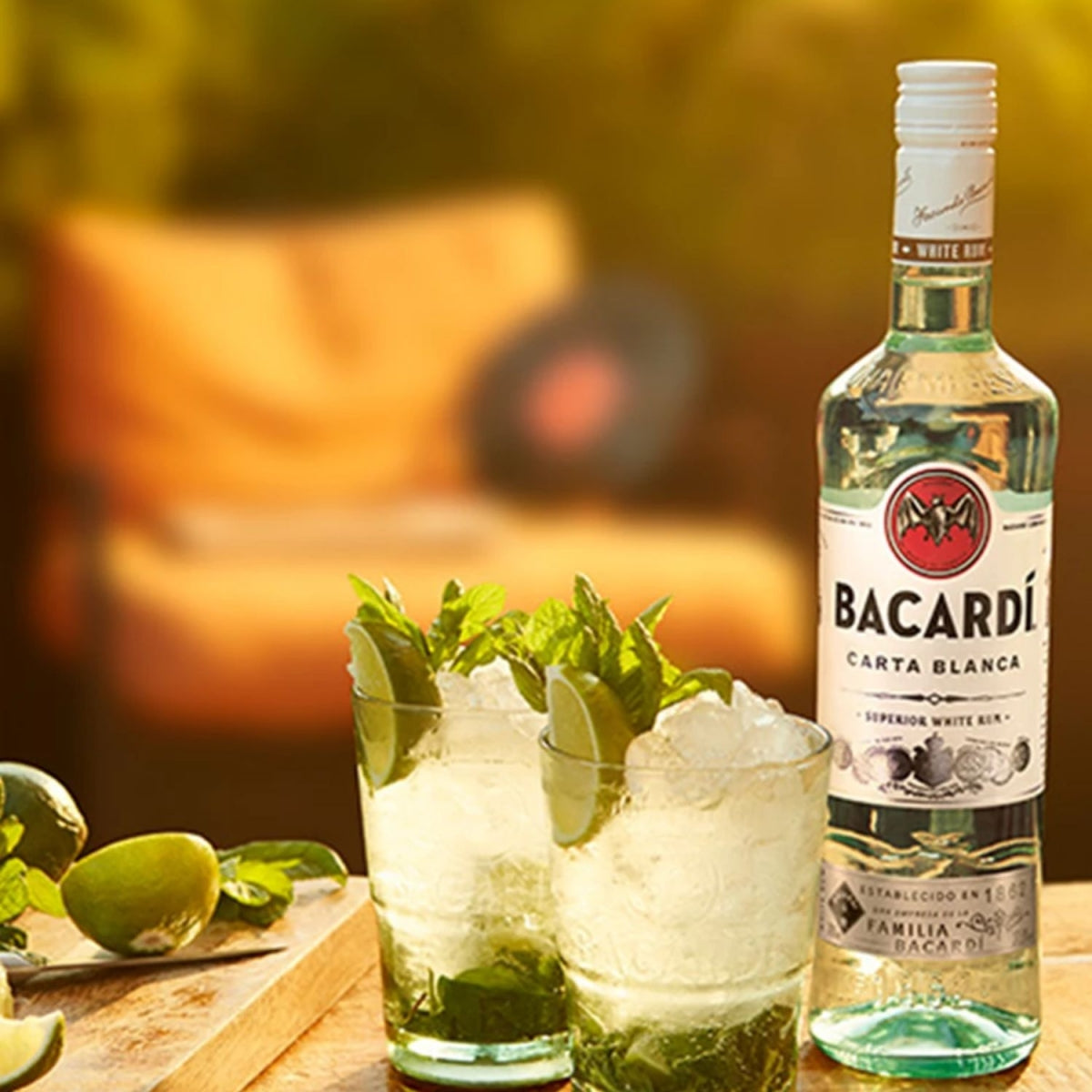 Garrafa de rum Bacardi Carta Blanca junto a copos de drink com gelo, limão e hortelã
