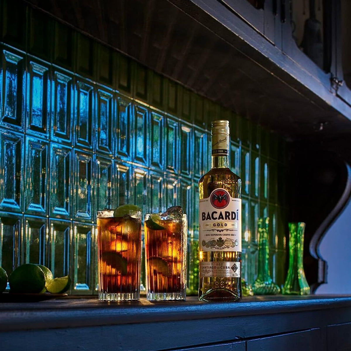 Garrafa Bacardi Carta Oro junto a dois drinks com gelo e limão em um bar.