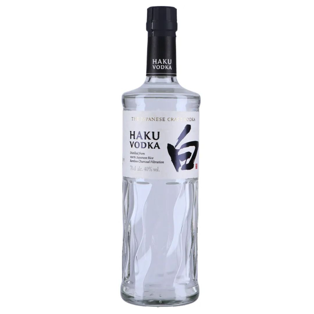 Garrafa de vidro transparente da vodka Haku com rótulo branco e tampa preta.